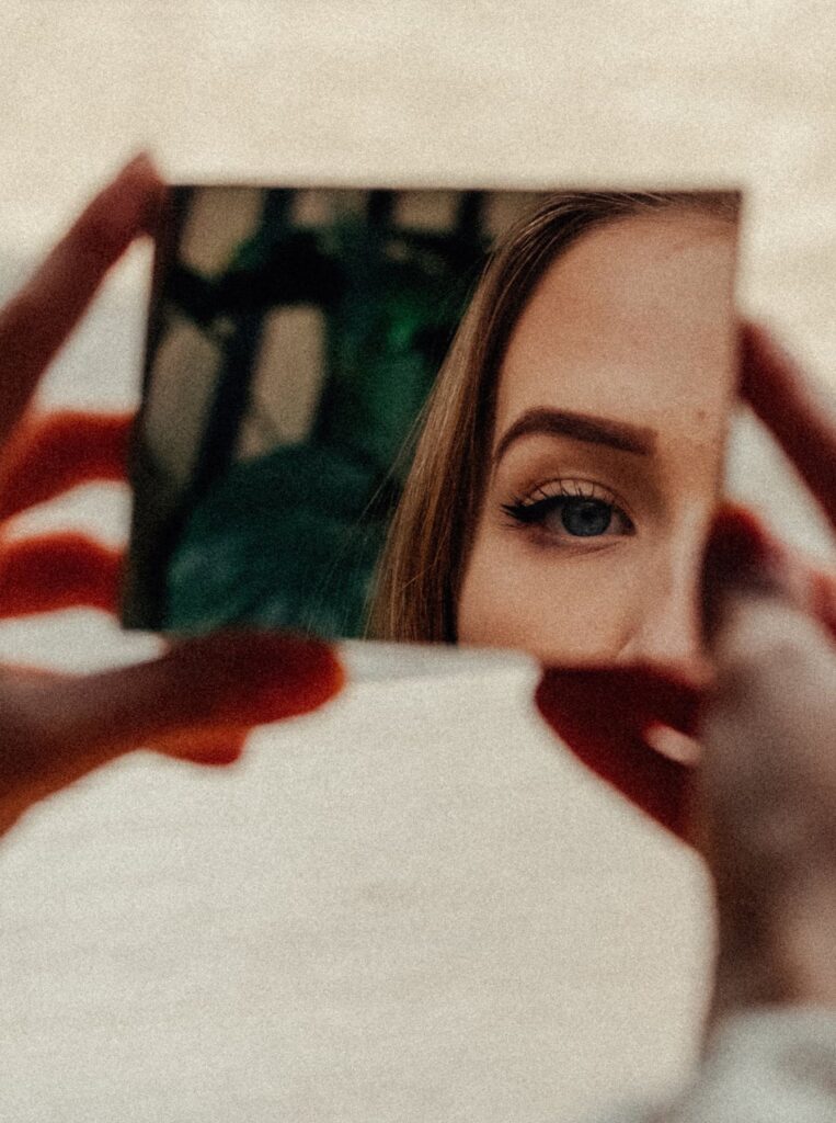 woman checking her eyes in a small hand mirror