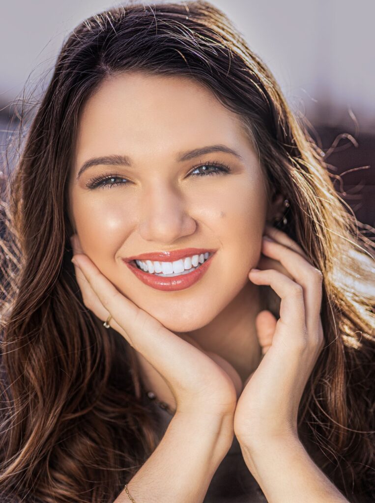 attractive woman smiling with her hands touching her face