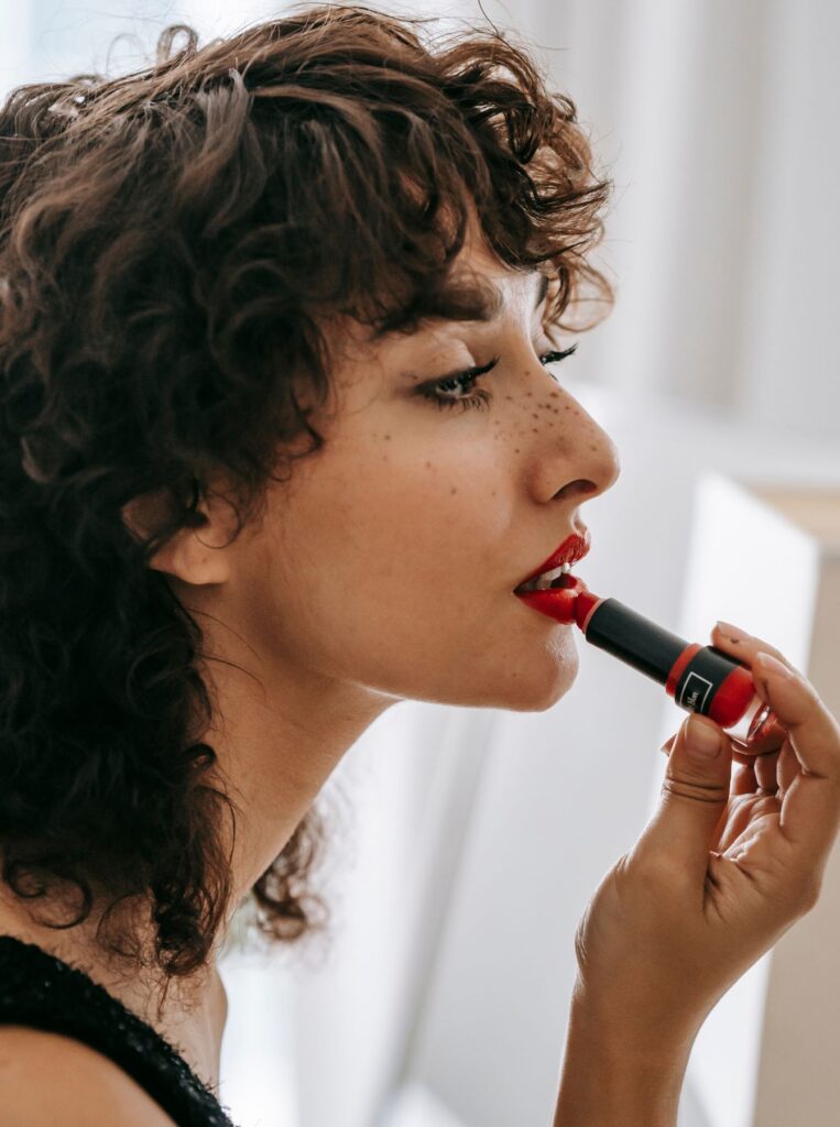 woman putting on a red lipstick