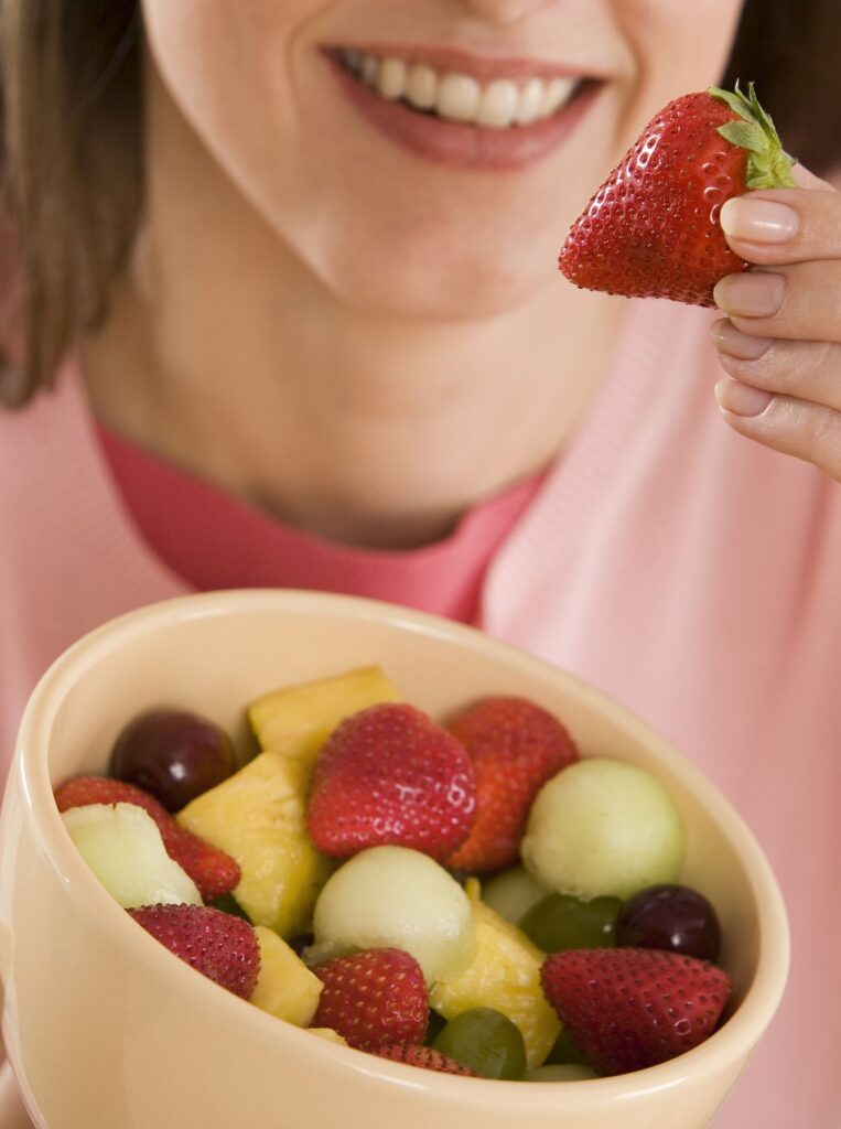 woman picking strawberry from a fruit bowl