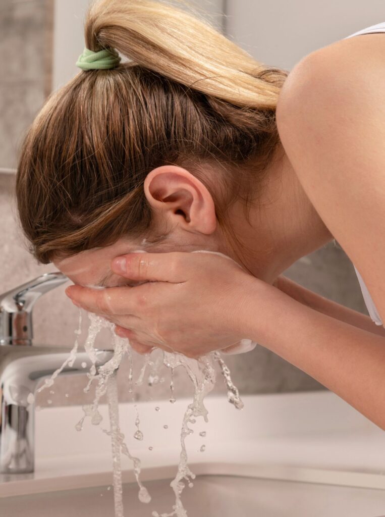 woman washing face with water