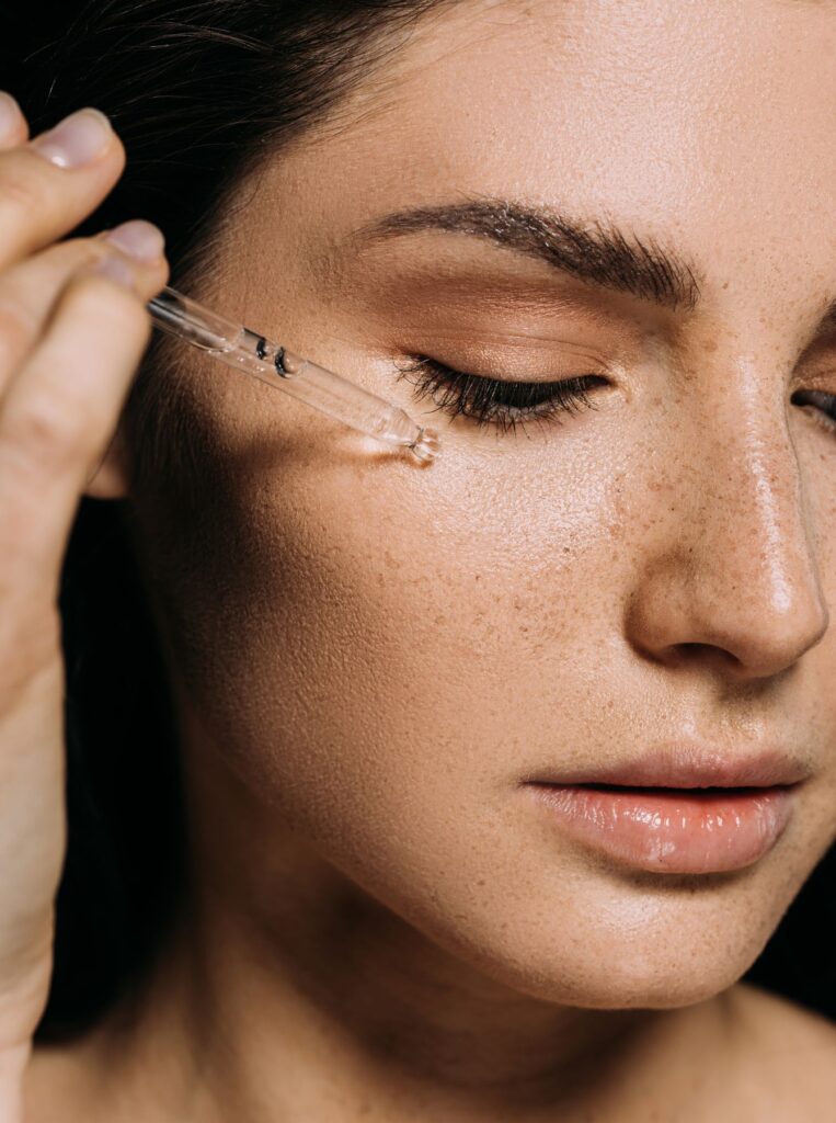 woman putting on a serum on face with a dropper