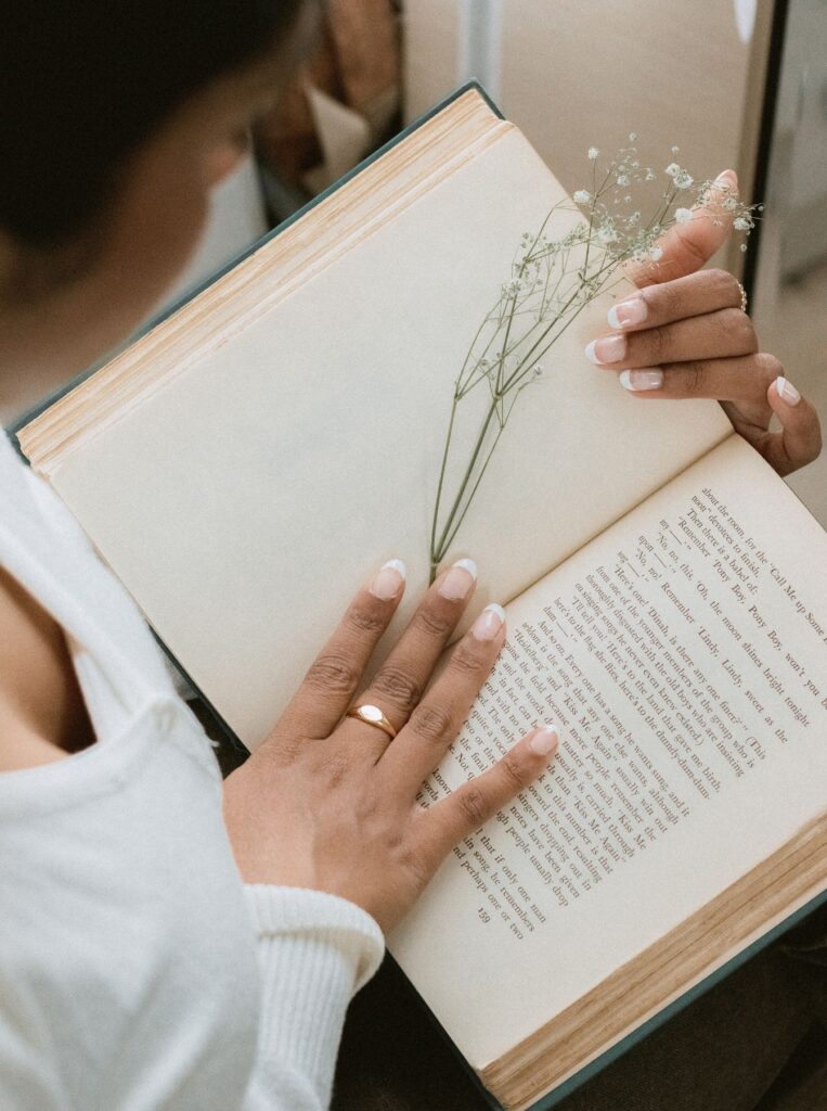 book open with hand and flower in it