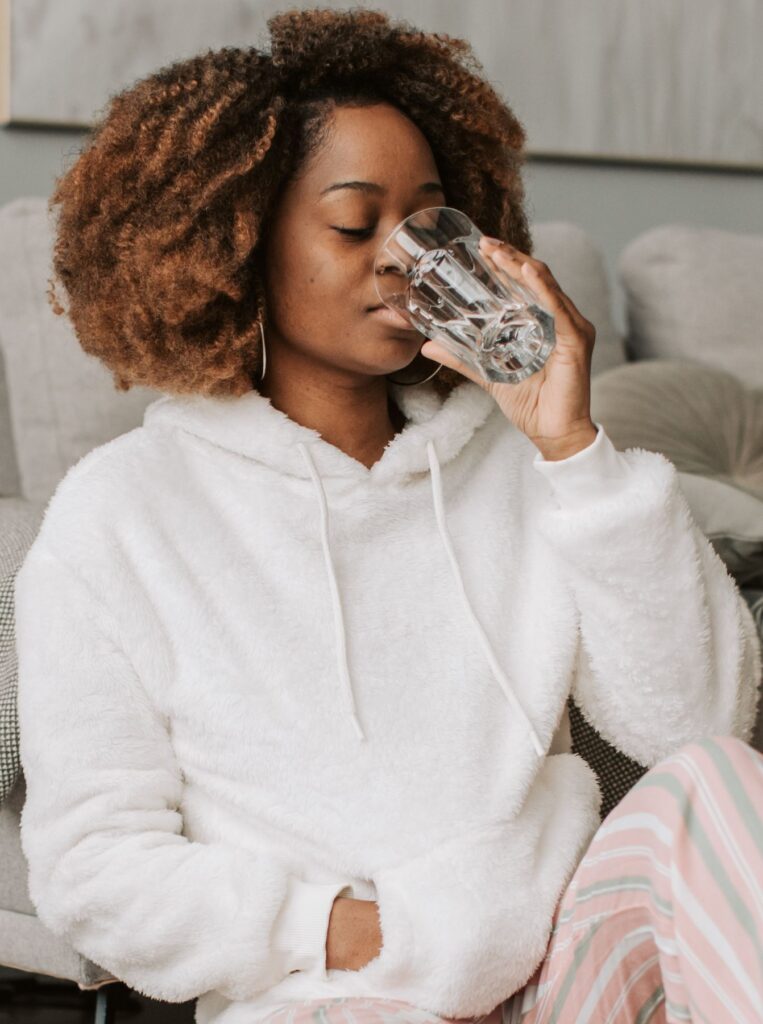 woman with curly short hair drinking water from glass