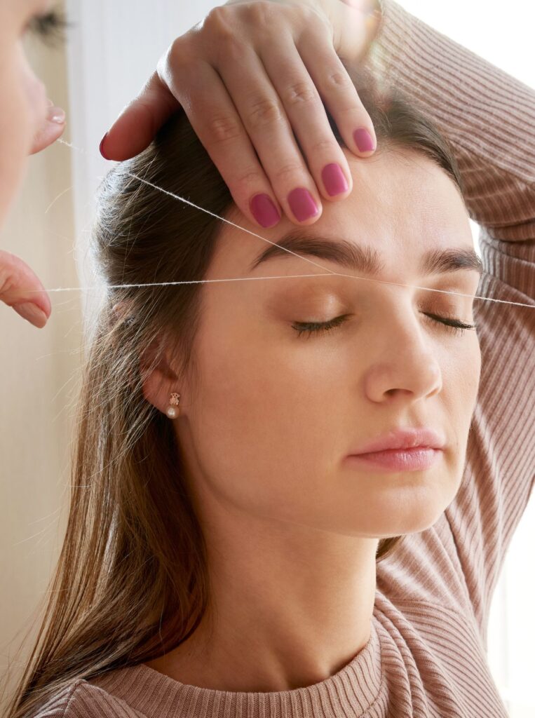 woman getting her eyebrows done by threading